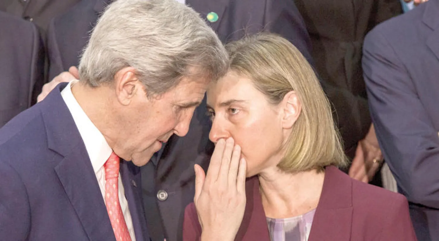 منسقة السياسة الخارجية بالاتحاد الأوروبي فيديريكا موغيريني تتحدث إلى وزير الخارجية الأميركي جون كيري خلال وقوف المشاركين في اجتماع باريس لالتقاط صورة جماعية لهم أمس (أ.ب)