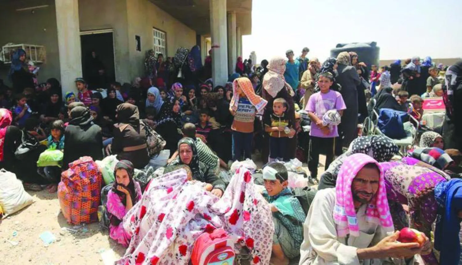 أطفال ونساء من العوائل الهاربة من الفلوجة.. وفي الاطار طفلة عراقية تسقي اخاها عصيرا بعد هروبهم من المدينة أمس ({الشرق الأوسط})