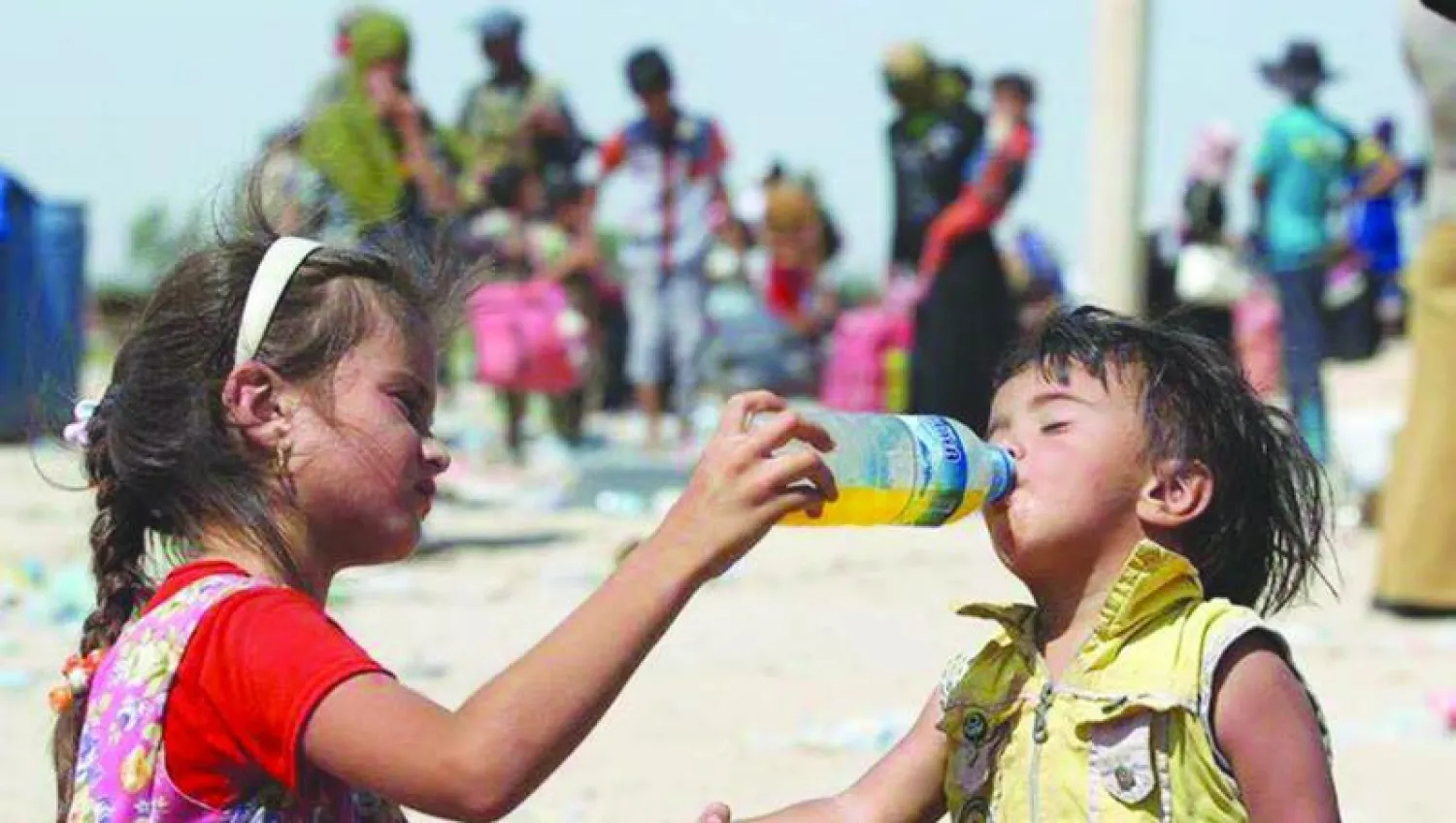 طفلة عراقية  تسقي اخاها عصيرا بعد هروبهم من المدينة أمس ({الشرق الأوسط})