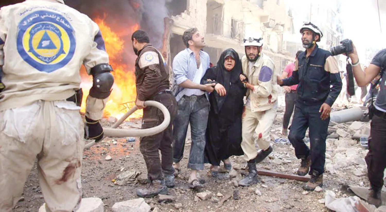 قوات الدفاع المدني تساعد امرأة من ضحايا غارتين جويتين بالبراميل المتفجرة على حي الشعار صباح أمس (مركز حلب الإعلامي) 