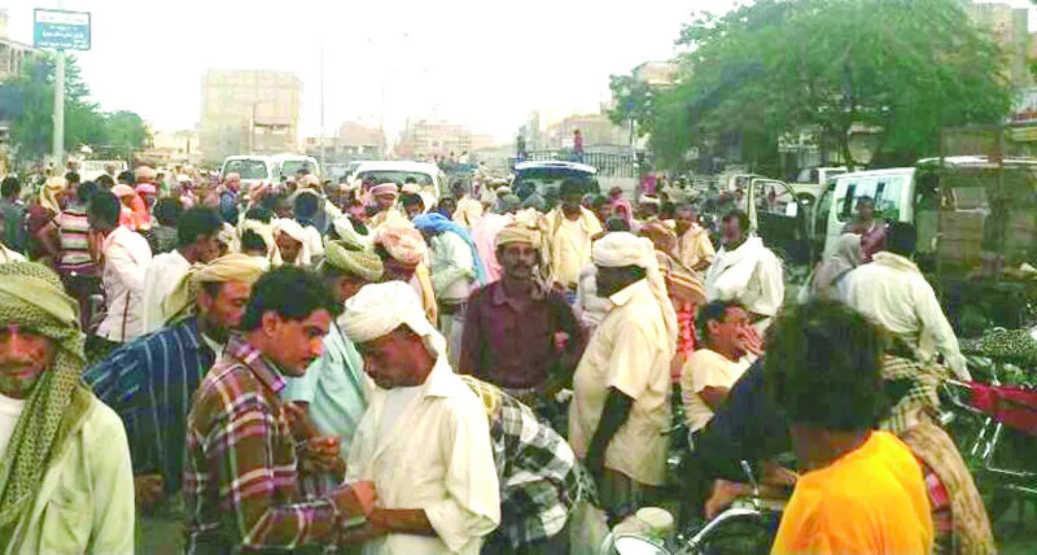 مواطنون يحاولون كسب العيش عبر الأعمال البسيطة في ساحة عامة بالحديدة أمس («الشرق الأوسط»)