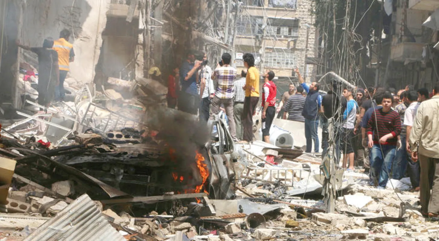 سكان حي بستان القصر الذي يتعرض لغارات دائمة من الطيران الروسي والنظامي يتفحصون آثار الدمار في صورة تعود لشهر أبريل الماضي (رويترز)