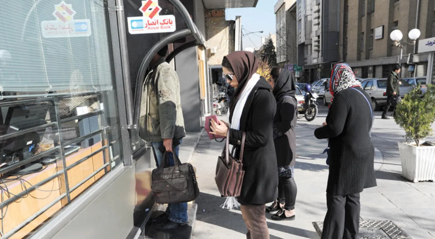إيرانيون یستخدمون جهاز صراف آلي أمام بنك في منطقة ونك شمال العاصمة طهران ديسمبر 2013 (غيتي)