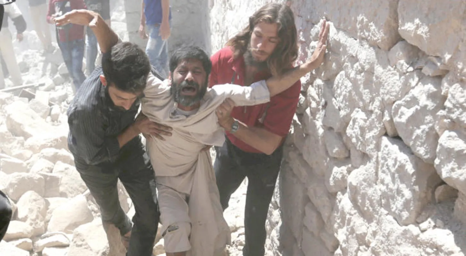 مواطنان يواسيان سوريا فقد ابنه في القصف الجوي الذي تعرضت له معرة النعمان في إدلب (رويترز)