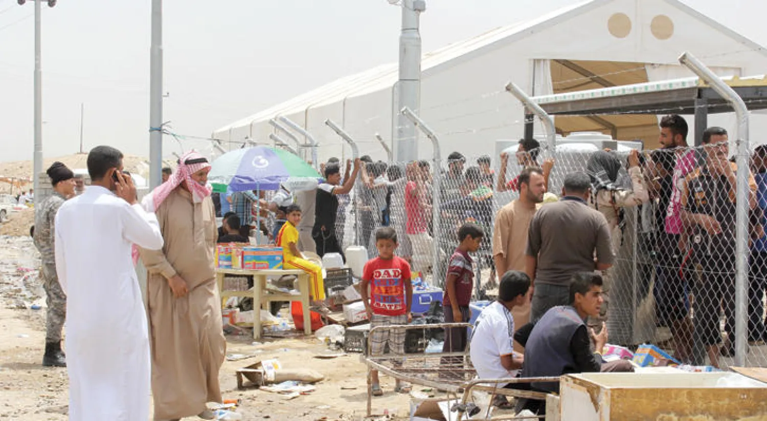 نازحون من الموصل ينتظرون إنهاء إجراءاتهم الأمنية لينقلوا إلى مخيم ديبكةجنوب غربي أربيل أمس («الشرق الأوسط»)