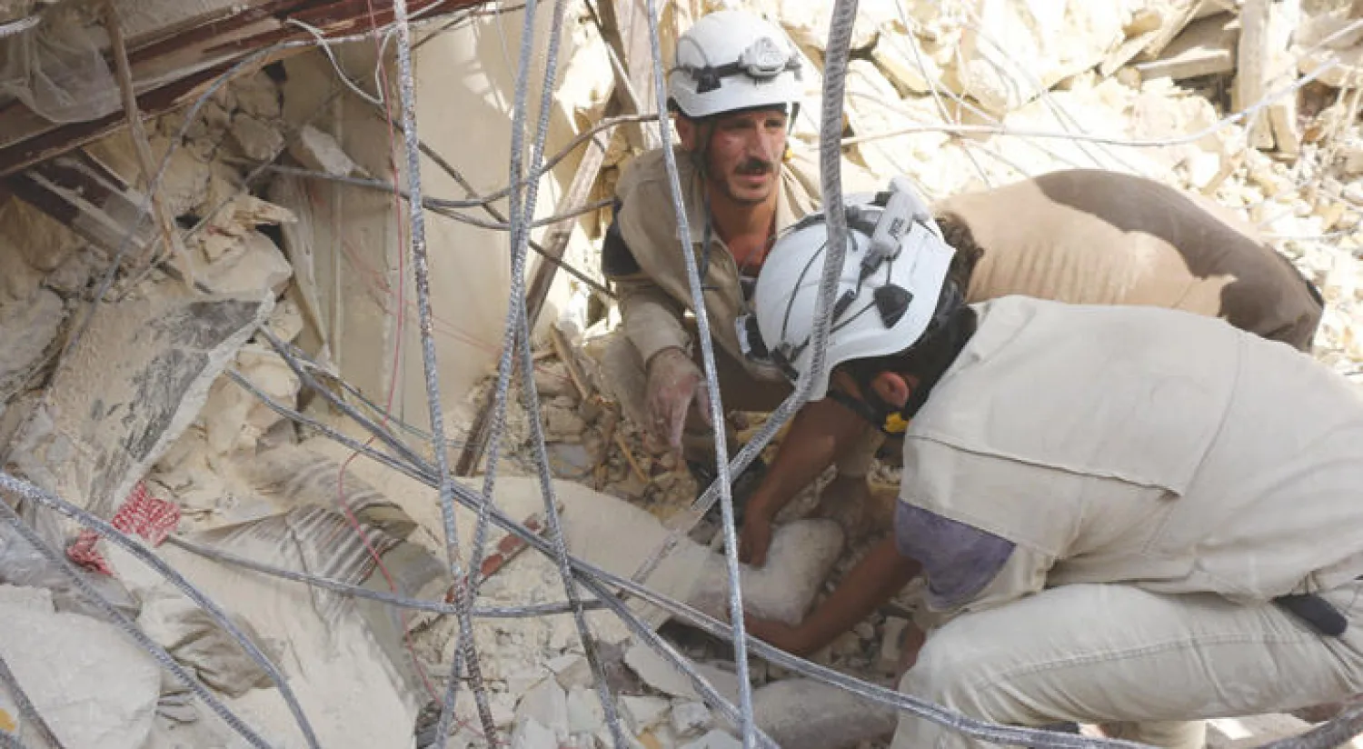 قوات الدفاع المدني تنتشل ضحايا من تحت ركام مبنى انهار في أعقاب غارة من طيران النظام بحي طريق الباب بحلب أمس (أ.ف.ب)