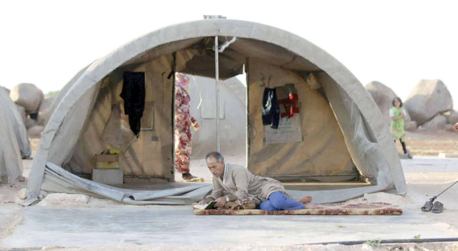 سوري يقرأ القرآن الكريم في رمضان داخل مخيم للنازحين جنوب محافظة إدلب (رويترز)