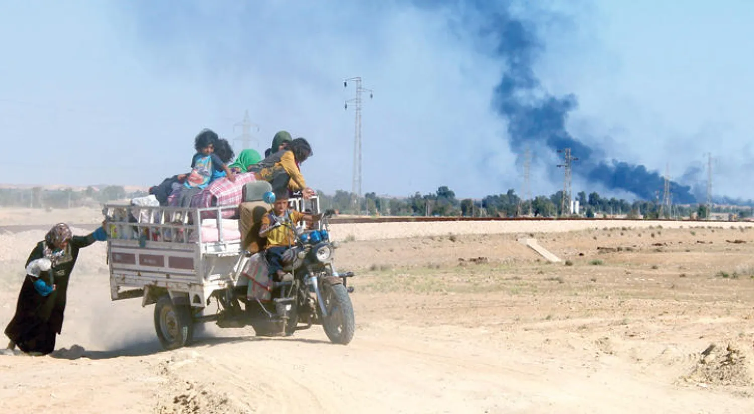 عراقية تدفع بعجلة بعد إعلان الحكومة إخلاء مئات من العراقيين من مدينة هيت في محافظة الأنبار للوصول إلى أماكن آمنة في محاولة لدخول المدينة وطرد {داعش} منها (أ.ف.ب)