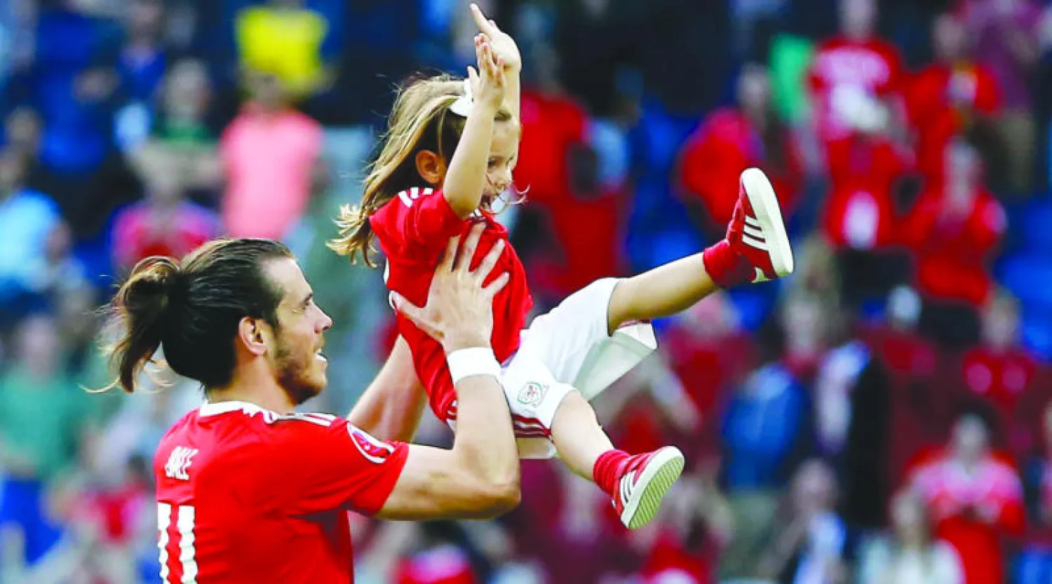 غاريث بيل يحتفل مع طفلته بعد أن قاد ويلز لربع النهائي (إ.ب.أ)