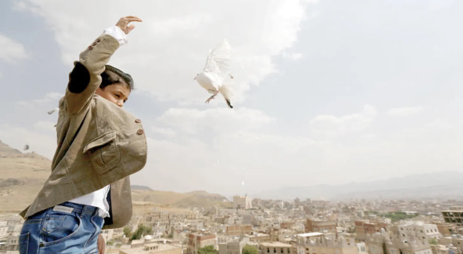 طفل يمني يطلق حمامة في الهواء لدفع اليمنيين في مشاورات الكويت للتوصل إلى اتفاق للسلام (رويترز)