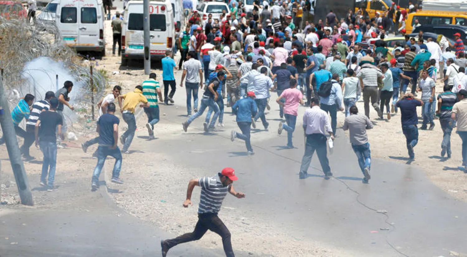 فلسطينيون يفرون من القنابل المسيلة للدموع أطلقتها عليهم القوات الإسرائيلية خلال مظاهرة في رام الله أمس (أ.ف.ب)