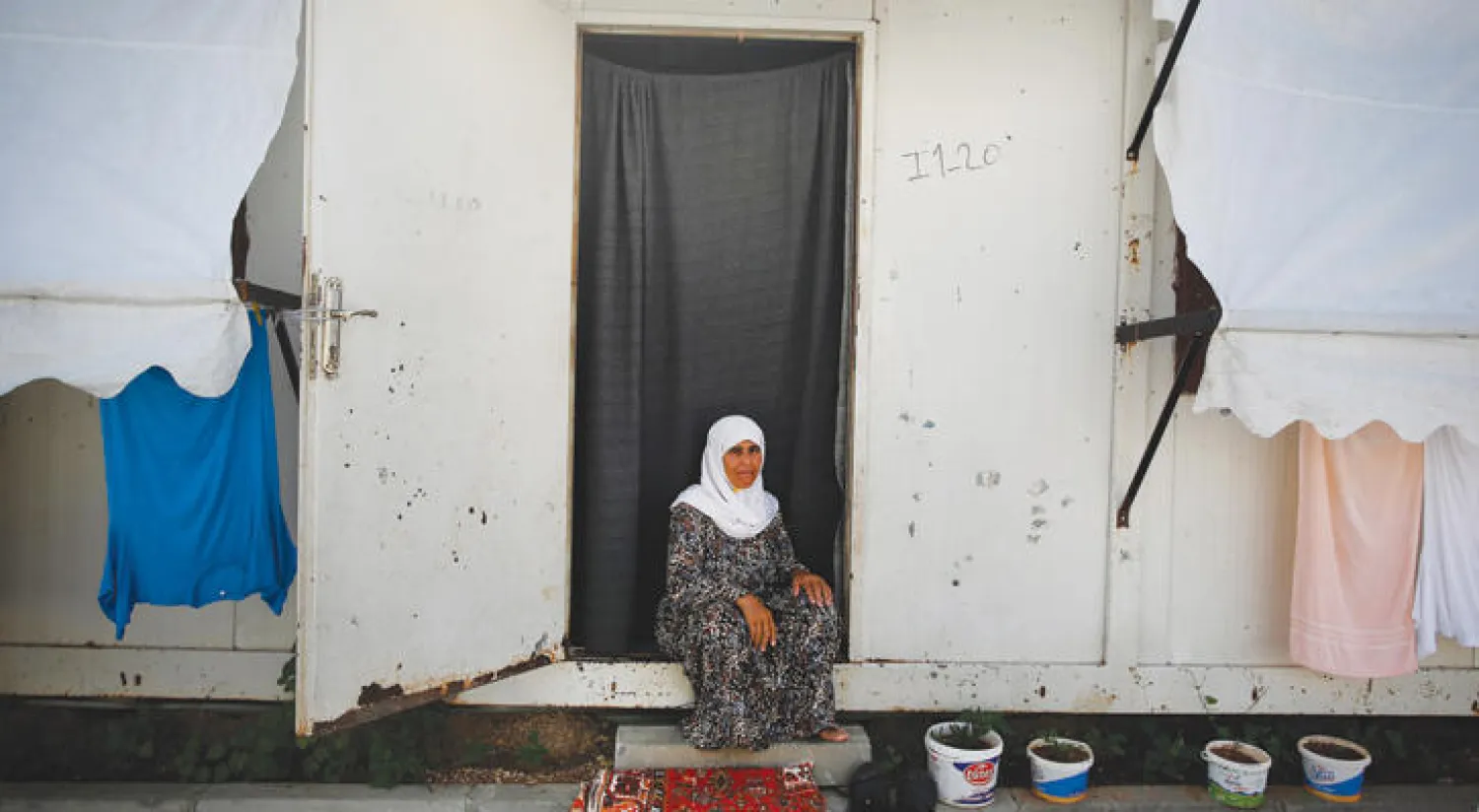 امرأة تجلس على مدخل سكنها في مخيم اونكوبينار التركي للاجئين السوريين على الحدود مع سوريا قرب كيليس (إ.ب)