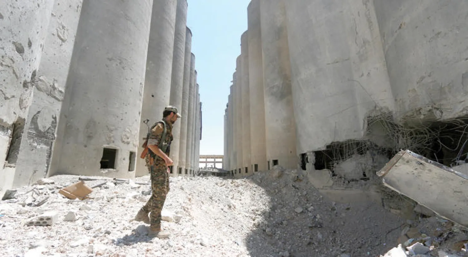 مقاتل من قوات سوريا الديمقراطية يمشي بين الصوامع والمطاحن في بلدة منبج بريف حلب بعد أن سيطرت القوات عليها قبل أيام (رودي)