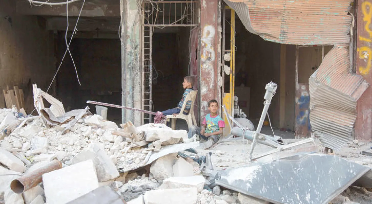 أطفال سوريون يجلسون بين أنقاض بناية تعرضت للقصف في حلب في وقت يكثر فيه الحديث عن تورط إيران في المأساة السورية (أ.ف.ب)