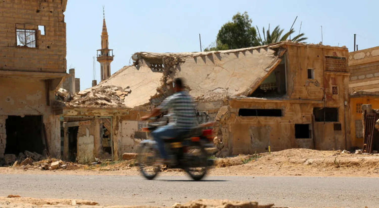 رجل من سكان داعل بريف درعا جنوب سوريا يجتاز بدراجته النارية الابنية المدمرة بفعل الغارات الجوية التي تستهدف البلدة الواقعة تحت سيطرة المعارضة (رويترز)