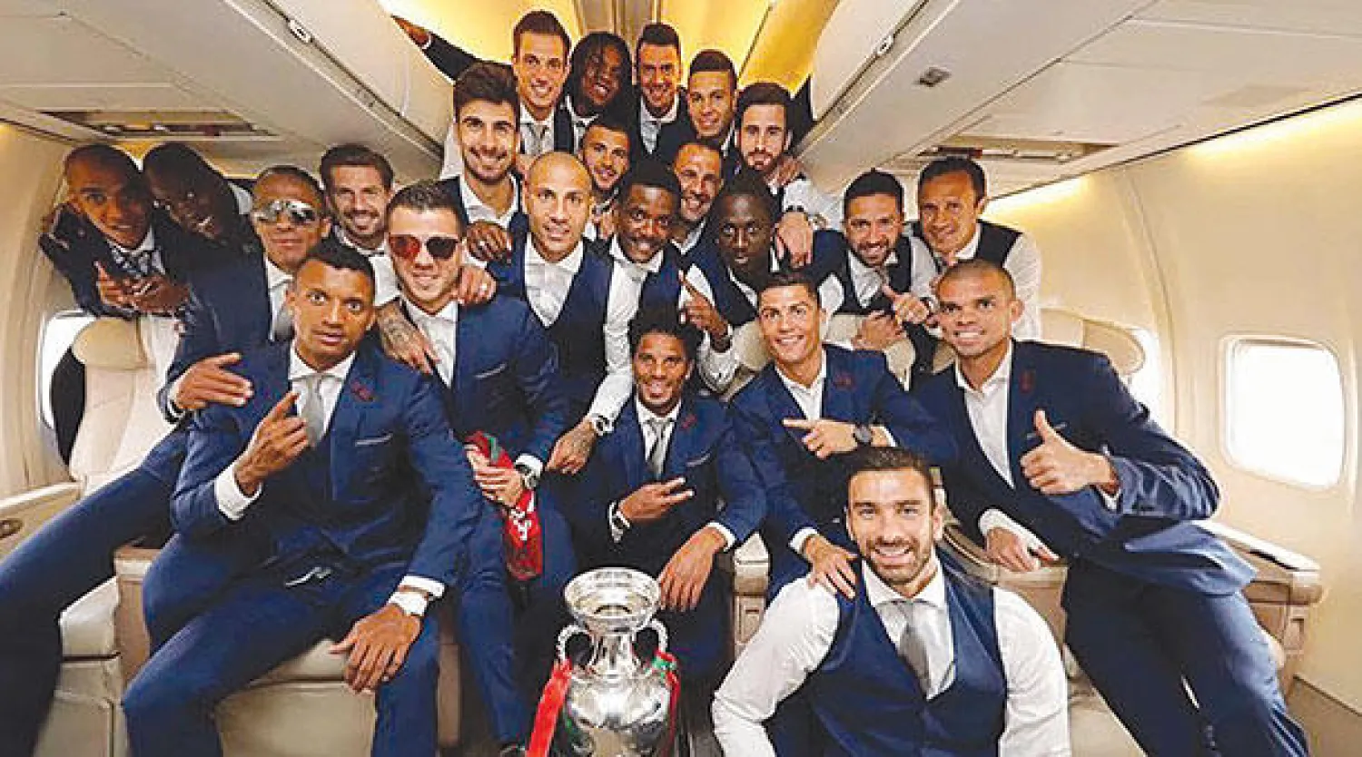 لاعبو منتخب البرتغال يحيطون بالكأس داخل الطائرة قبل هبوطهم في مطار لشبونة (أ.ف.ب)