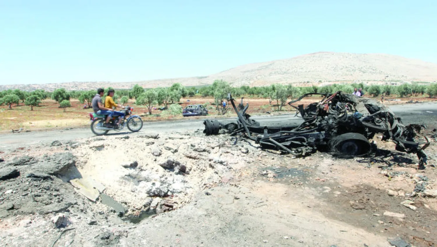 شابان على دراجة نارية في قرية ترمانين بريف إدلب شمال سوريا (رويترز)