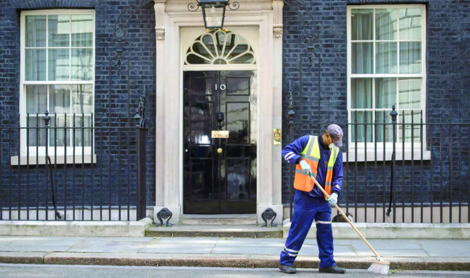عامل ينظف خارج «10 داوننغ ستريت» (مقر الحكومة) في لندن أمس أثناء ترؤس كاميرون آخر اجتماع حكومي له داخل المبنى (أ.ف.ب)