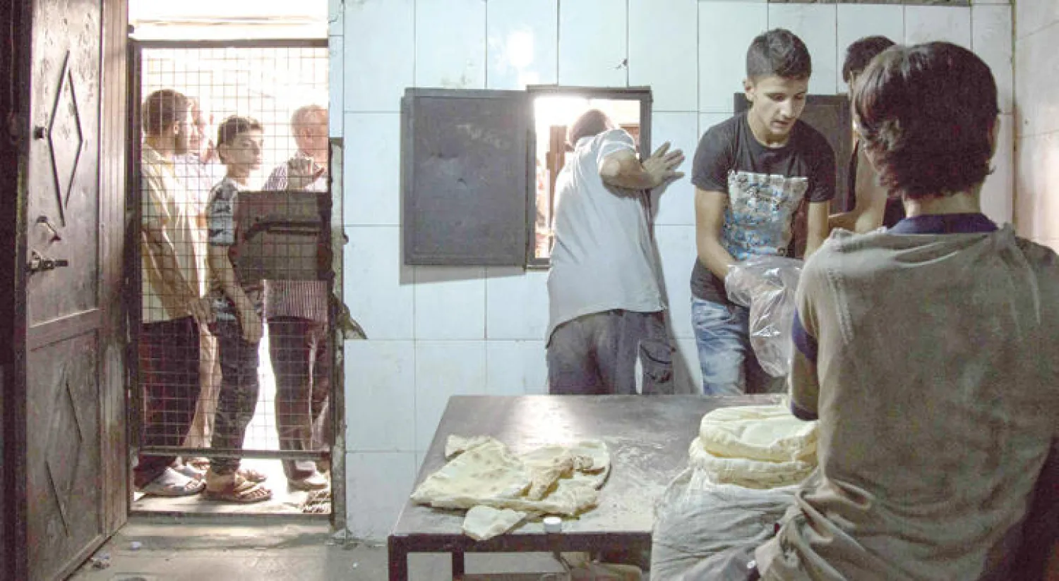 عاملون في مخبز بمنطقة سيطرة المعارضة في مدينة حلب، يهيئون حصص الخبز أول من أمس (أ.ف.ب)