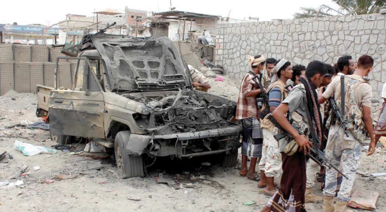 جنود يمنيون يقفون أمام حطام سيارة تعرضت للتفجير قرب عدن (أ.ف.ب)