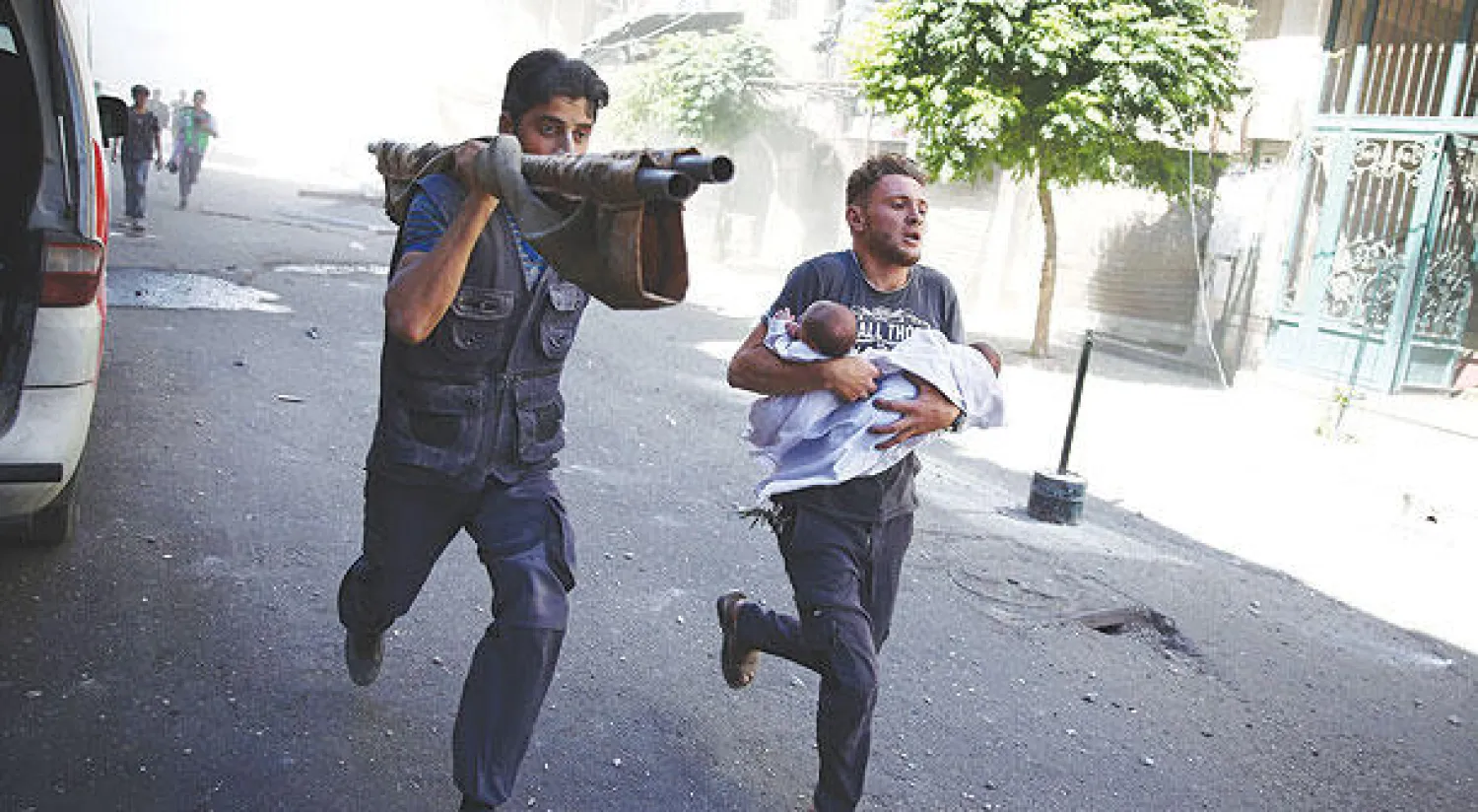 سوريان يحملان طفلين في عملية اجلاء أثناء القصف الجوي على بلدة دوما أمس (أ.ف.ب)