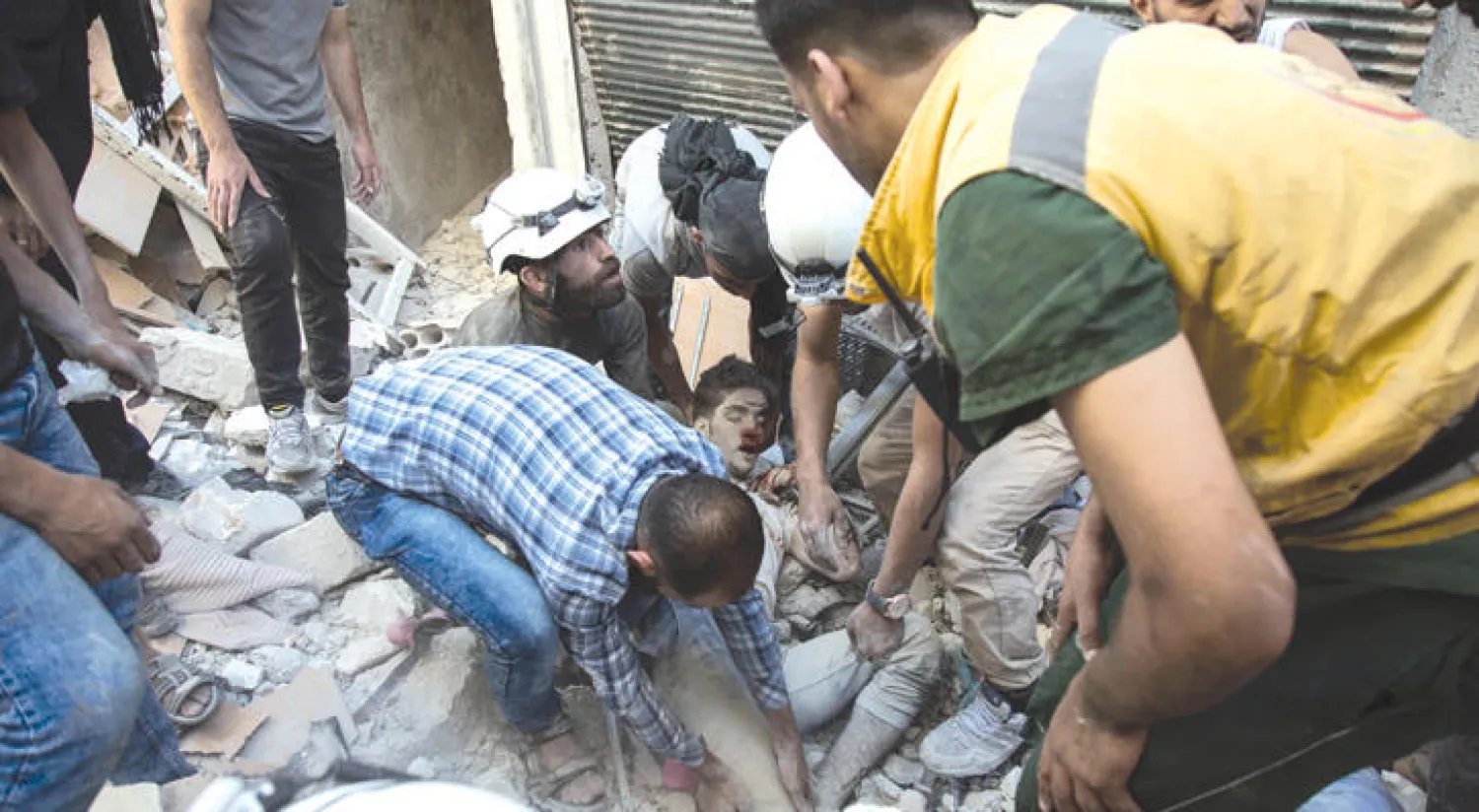 متطوعون سوريون يحاولون إخراج طفل من بين انقاض بناية تعرضت للقصف في حلب أمس (أ.ف.ب)