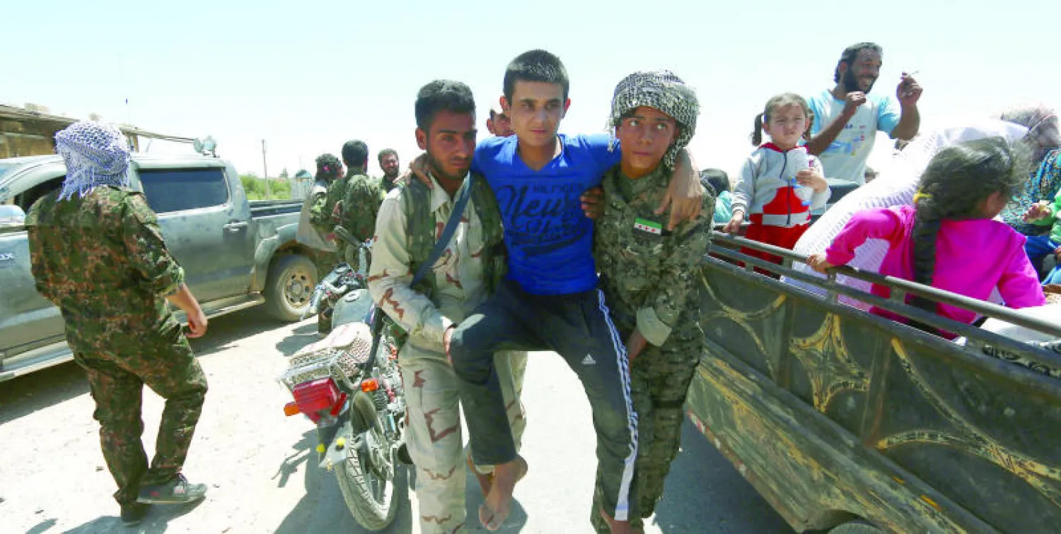 «قوات سوريا الديمقراطية» تساعد مدنيًا مصابًا في الخروج من بلدة منبج ضمن مدنيين آخرين تجمعوا على متن عربات نقل (رويترز)