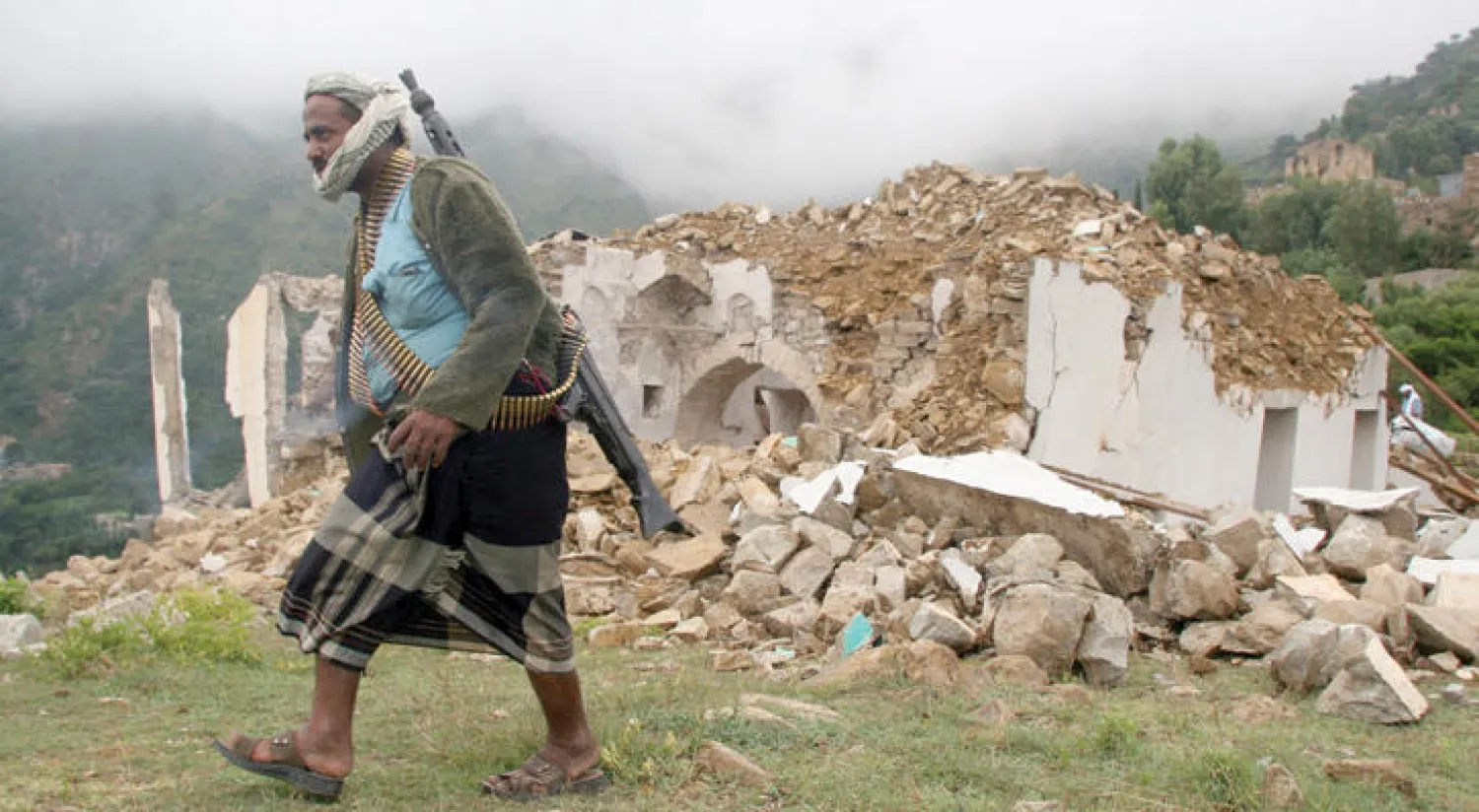 مقاتل موالٍ للحكومة اليمنية يمر أمس أمام مسجد مدمر بفعل الحرب في منطقة الصراري التابعة لمحافظة تعز التي حررتها قوات الشرعية قبل أيام (رويترز)