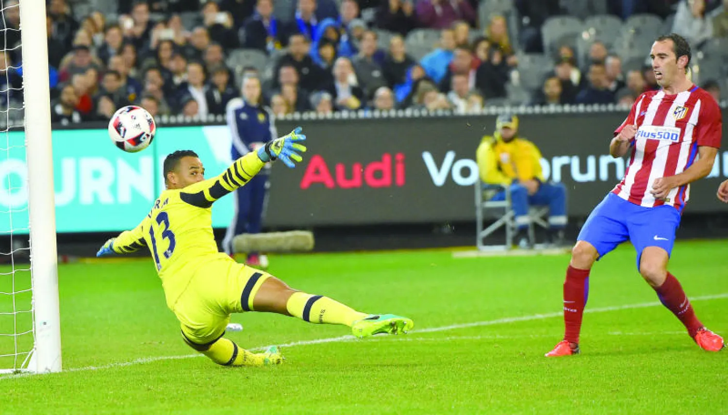 غودين لاعب أتلتيكو يسجل من فوق فورم حارس توتنهام (أ.ف.ب)