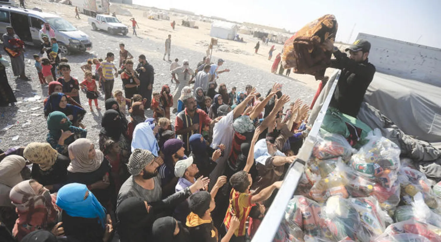 نازحون من معارك الشرقاط جنوب الموصل يتسلمون مواد إغاثة على أطراف المدينة أول من أمس (رويترز)