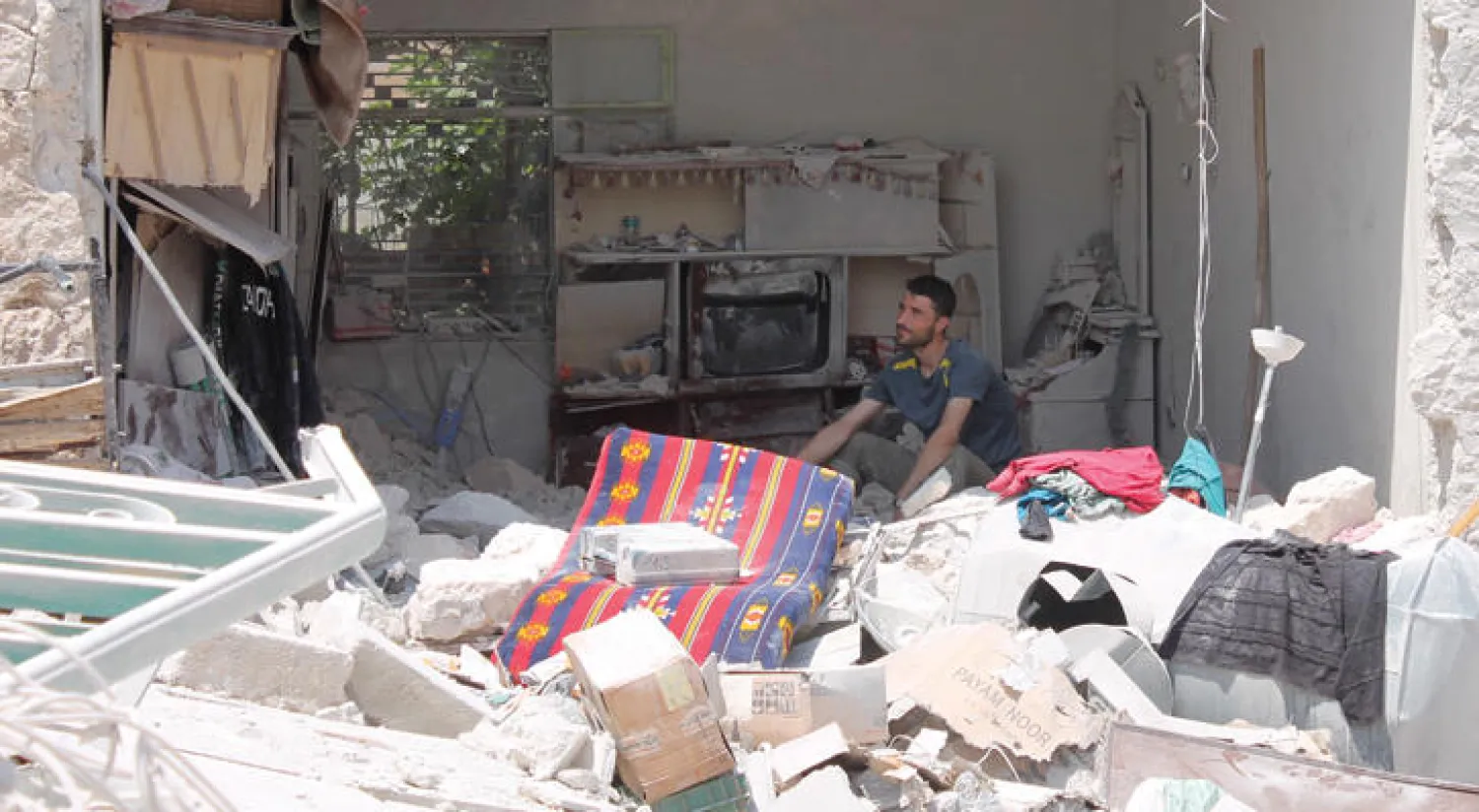 سوري يجلس بين انقاض منزله المدمر بعد قصف الطائرات الروسية لمنطقة اتارب في حلب أمس ({غيتي})
