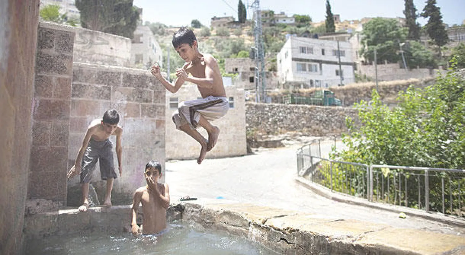 أطفال فلسطينيون يسبحون في حوض ماء بموقع أثري في قرية بتير القديمة (أ.ف.ب)
