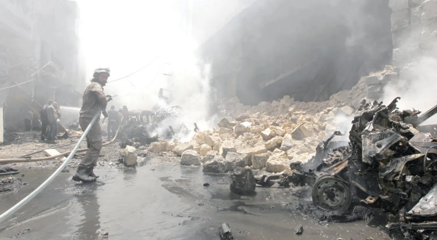 الدفاع المدني في إدلب شمال سوريا يطفئ النيران التي اندلعت في أعقاب غارة جوية من طيران النظام على شارع الجلاء المزدحم بالسكان (رويترز)