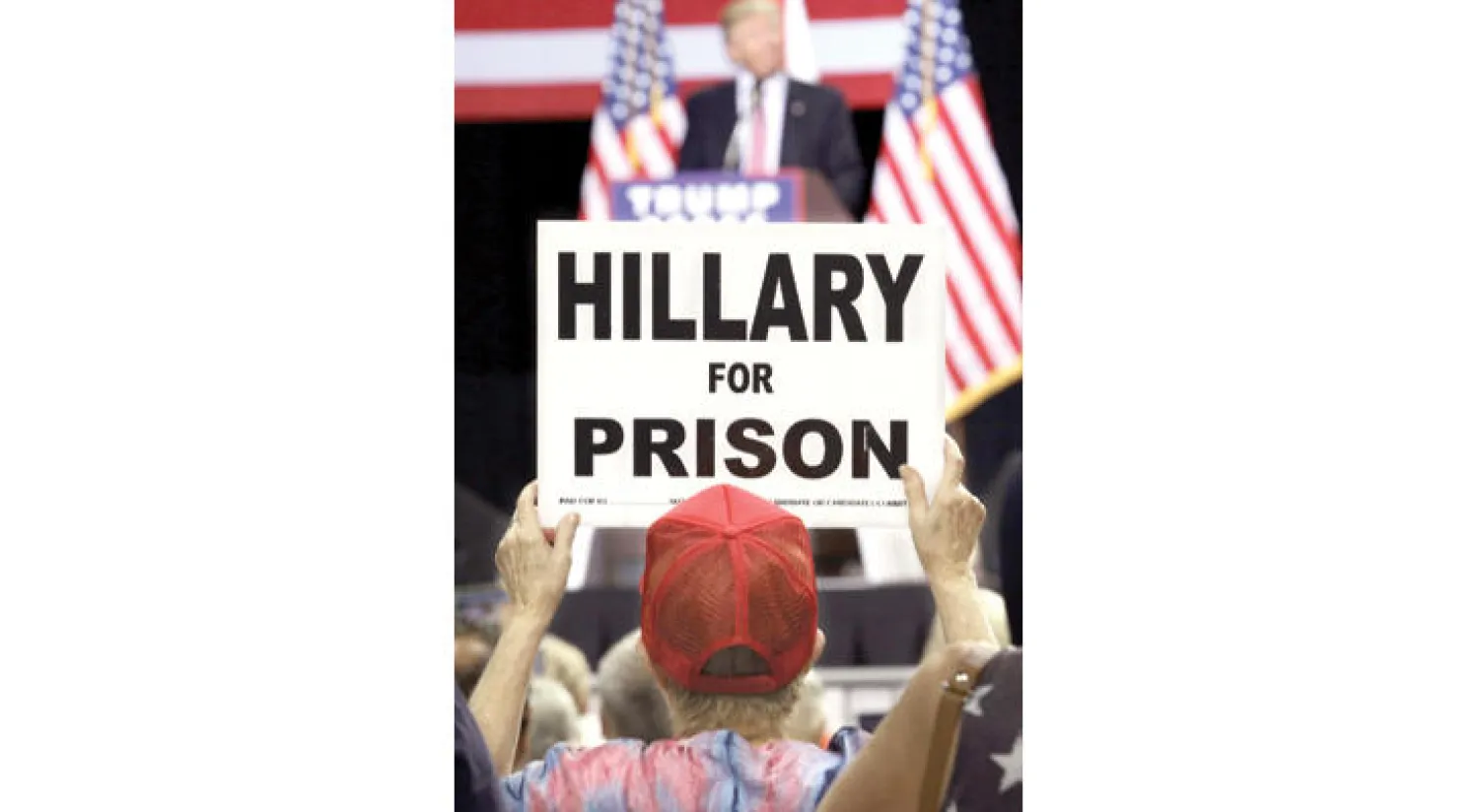 أحد المؤيدين لحملة ترامب يرفع لافتة كتب عليها عبارة «هيلاري إلى السجن» (أ.ف.ب)