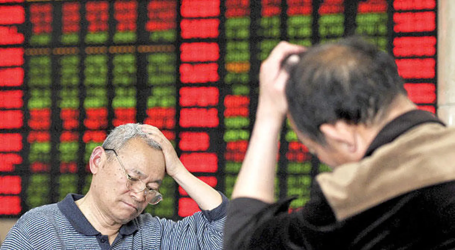 مستثمران في البورصة الصينية تبدو عليهما علامات الإحباط لخسارة أموالهم (رويترز)