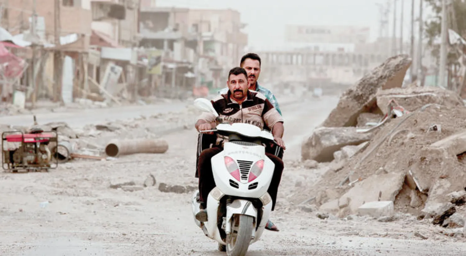 عنصرا أمن يستقلان دراجة نارية وسط الدمار في أحد شوارع الرمادي (أ.ب)