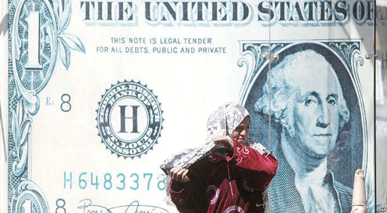 امرأة مصرية تمر أمام ملصق ضخم للدولار الأميركي أمام مكتب صرافة بالقاهرة