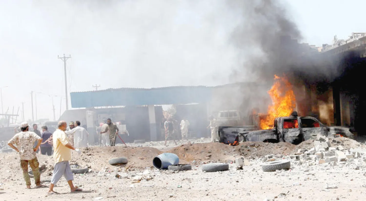 ليبيون يحاولون إطفاء حرائق اندلعت عقب تفجير سيارة في الغربية التابعة لسرت (رويترز)