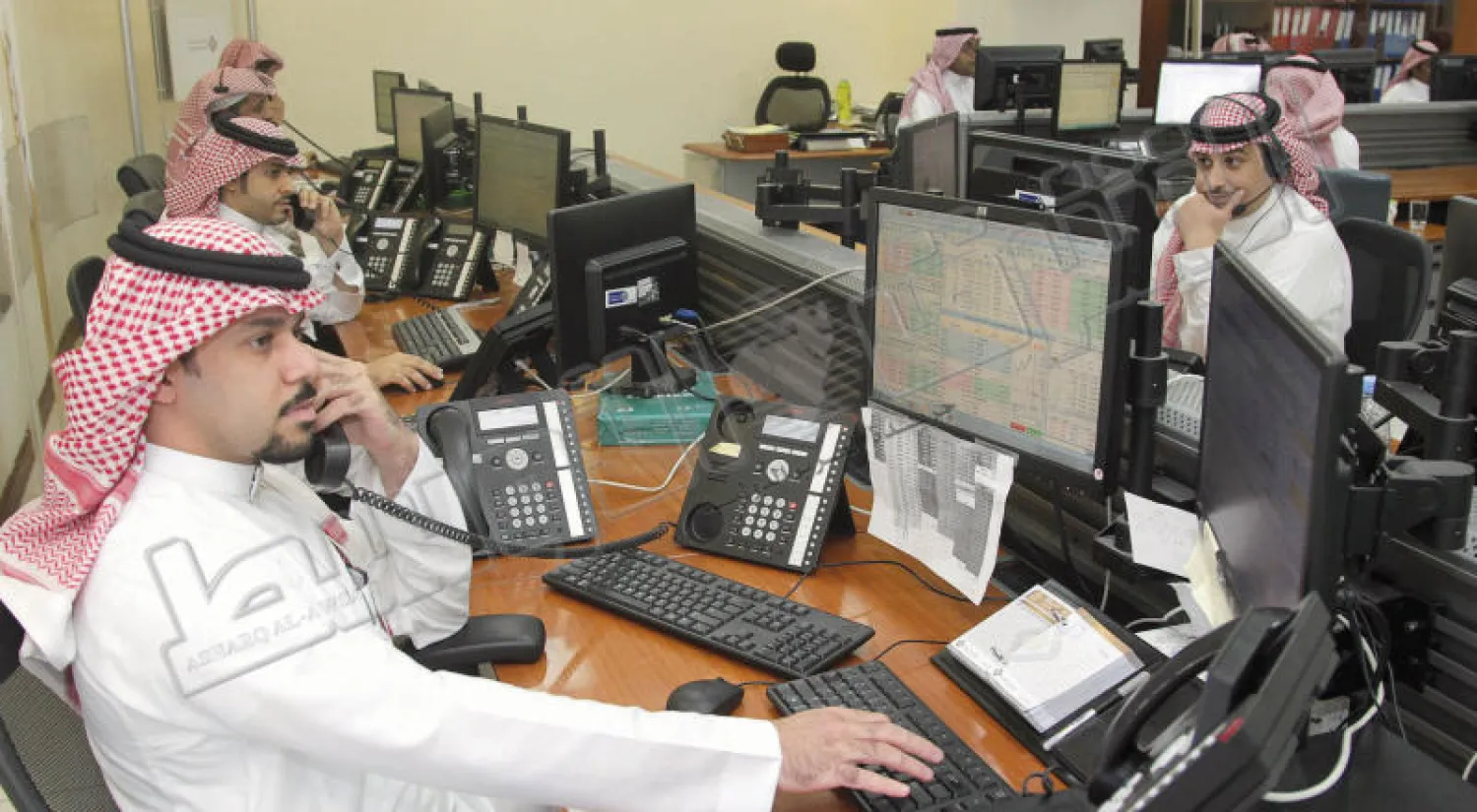 مستثمرون سعوديون يتابعون تحركات أسعار الأسهم على شاشة التداول (خالد الخميس)