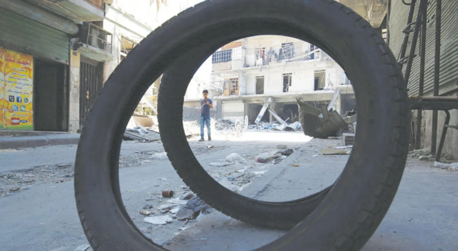 طفل يجتاز محلات وأبنية مدمرة بفعل غارات النظام وروسيا في القسم الذي يخضع لسيطرة المعارضة بمدينة حلب (رويترز)