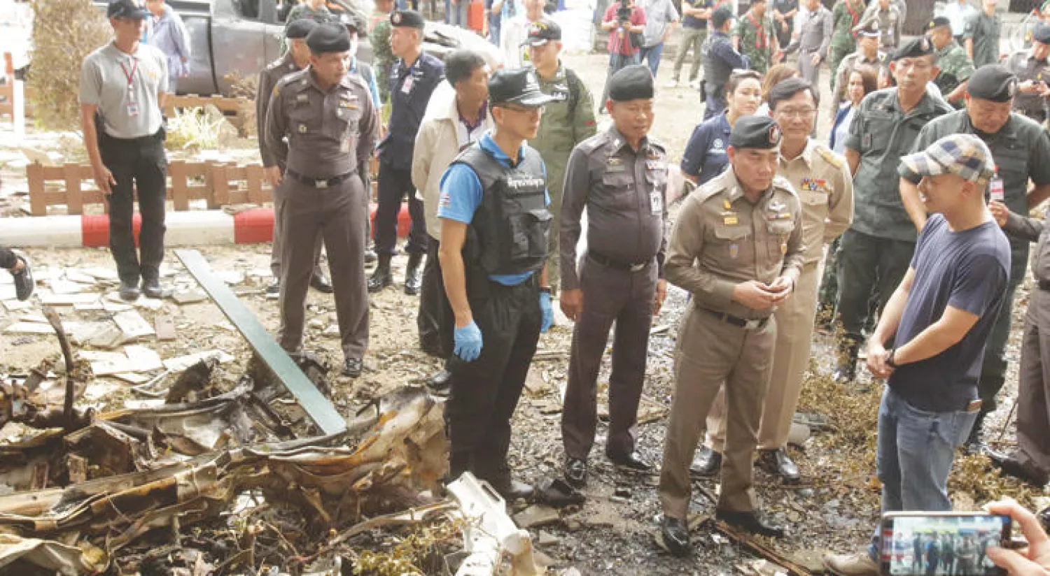 أحد قادة الشرطة التايلندية مع عناصره في موقع التفجير الذي استهدف ضاحية باتاني جنوب البلاد أمس (أ.ف.ب)