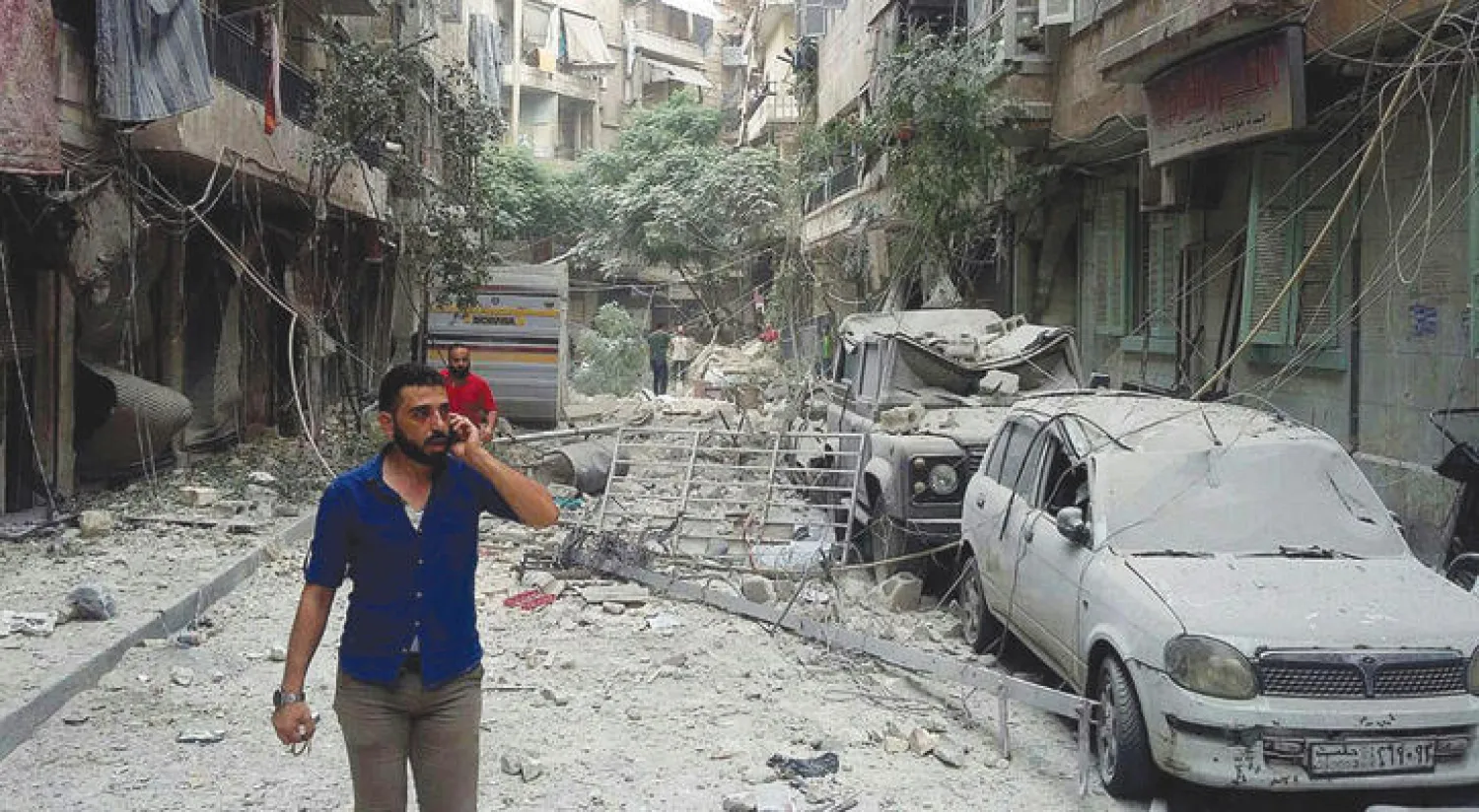 مواطنون سوريون وسط الدمار الذي سببته صواريخ سقطت على أحياء سكنية في حلب (إ.ب.أ)