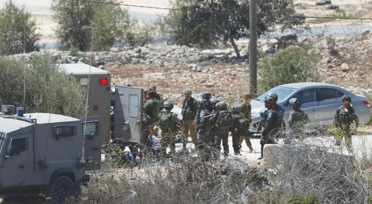 قوات الاحتلال الإسرائيلي تحيط بجثة فلسطيني أعدمته ميدانيًا عند مدخل قرية سلواد أول من أمس (أ.ف.ب)