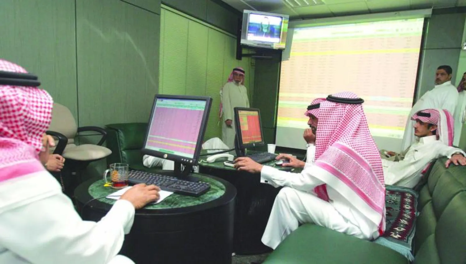 مستثمرون سعوديون يتابعون أسعار الأسهم على شاشة للتداول