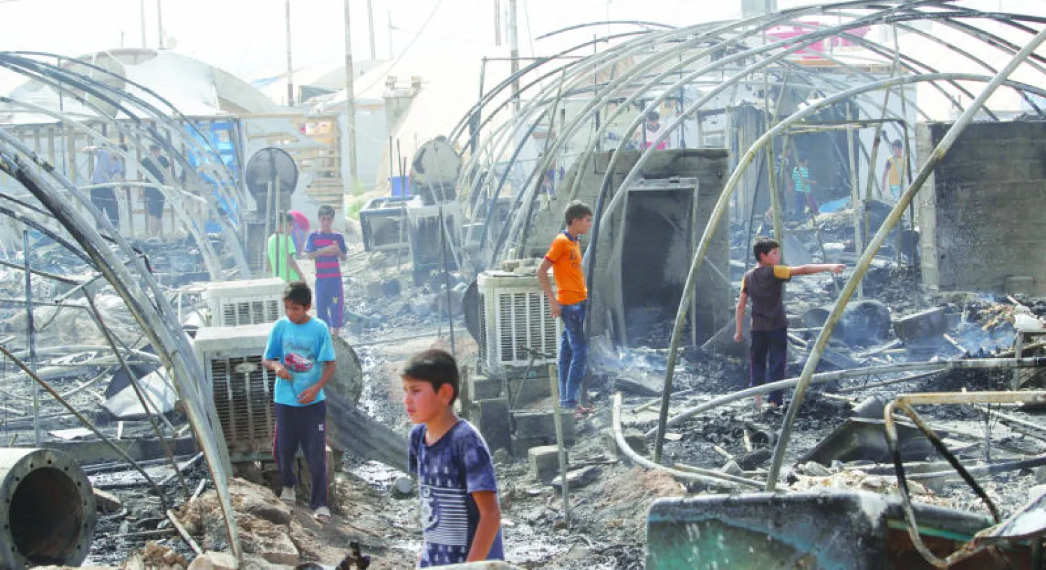 نازحون في مخيم يحياوة قرب كركوك يعاينون آثار حريق اندلع في المخيم أمس والتهم 70 خيمة (رويترز)