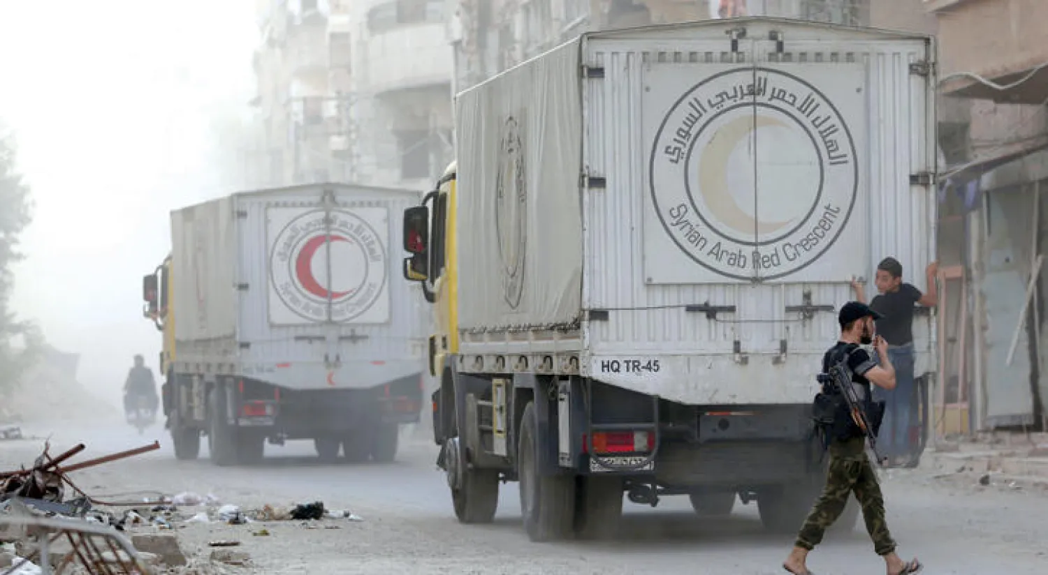 طفل سوري تعلق بخلفية سيارة للهلال الأحمر السوري أوصلت مساعدات لبلدة حرستا شمال شرقي دمشق أول من أمس (أ.ف.ب)