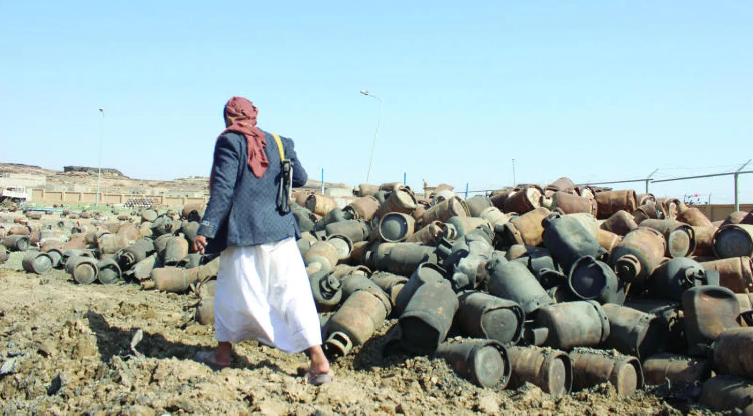 حوثي حاملا سلاحه يسير بالقرب من محطة غاز تعرضت للدمار بسبب الاشتباكات (رويترز)