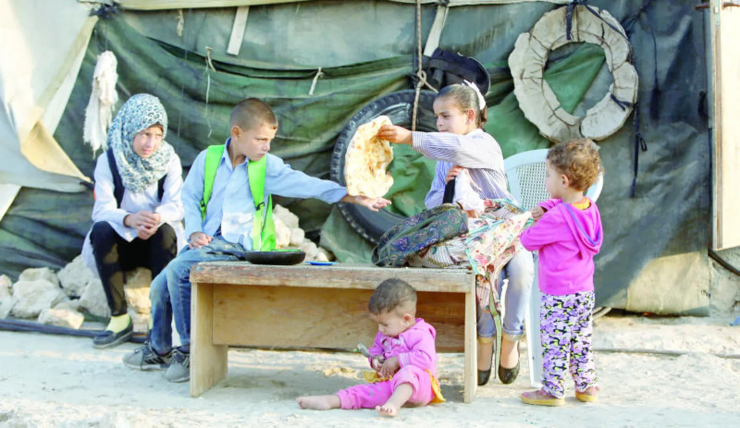 أطفال فلسطينيون يتناولون وجبة الإفطار قبل توجههم إلى المدرسة في بلدة سوسيا مع بدء الموسم الدراسي (رويترز)