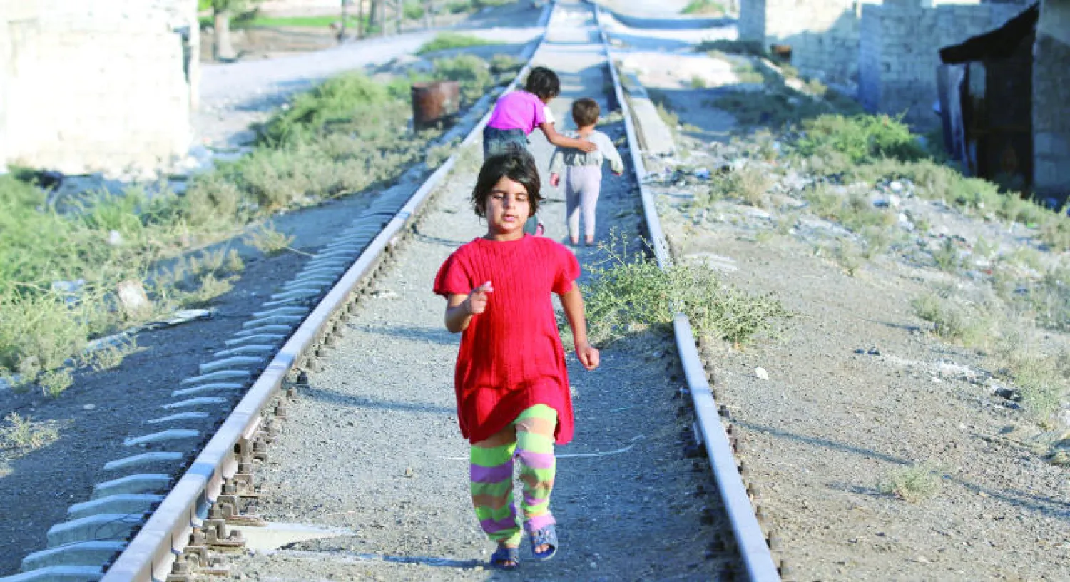 أطفال يلهون على خط معطل للسكك الحديدية في منطقة الشيخ سعيد بشمال حلب أمس (رويترز)