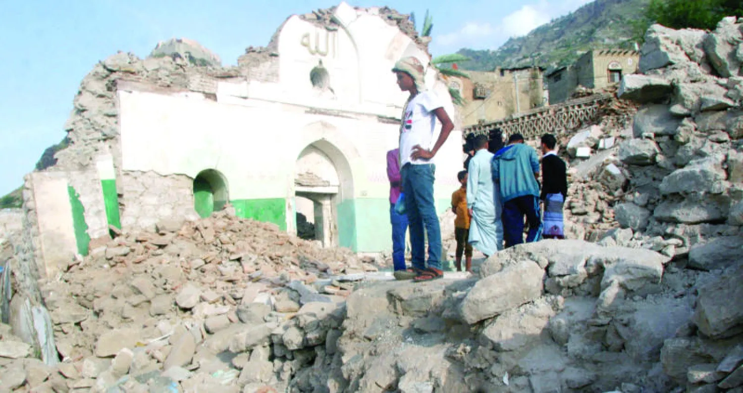 مواطنون يمنيون مجتمعون حول أنقاض مسجد تعرض للتدمير في تعز (رويترز)